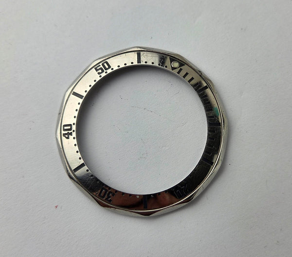 Silver watch bezel with numerical markings on a gray background