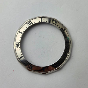 Silver watch bezel with numerical markings on a gray background